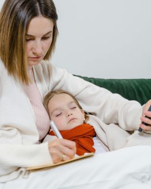 A woman sits on a couch with a child, holding a cell phone and engaging in conversation