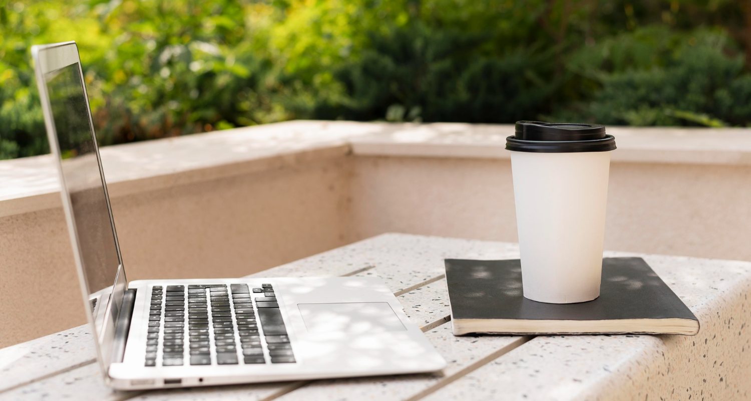 A laptop alongside a steaming cup of coffee rests on a table, suggesting a productive work environment