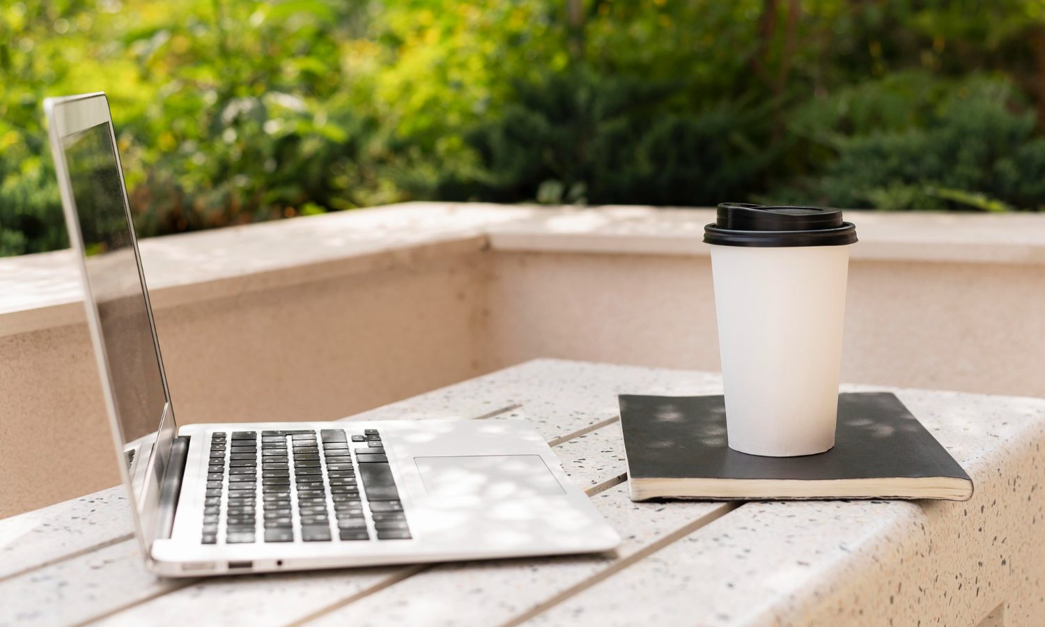 A laptop alongside a steaming cup of coffee rests on a table, suggesting a productive work environment
